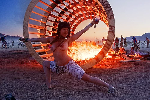 burning man - topless woman dancing at dusk in front of burning cylindrical wooden frame, burning, cylinder, cylindrical, dancing, dusk, fire, frame, heather, stretching, topless, woman, wood, wooden