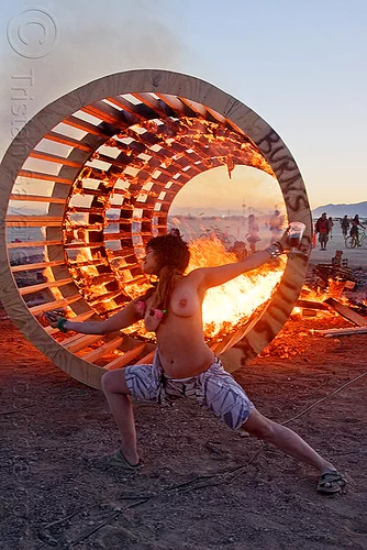 burning man - topless woman dancing at dusk in front of burning cylindrical wooden frame, burning, cylinder, cylindrical, dancing, dusk, fire, frame, heather, stretching, topless, woman, wood, wooden