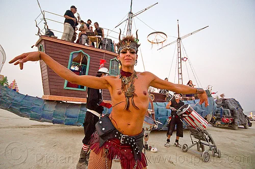 burning man - woman dancing, attire, burning man art cars, burning man outfit, dancing, fishyboat art car, headdress, marching band, mutant vehicles, narwhal art car, necklaces, topless, woman